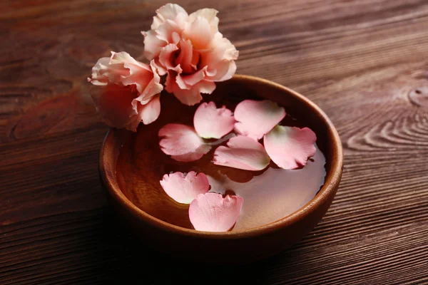 粉红玫瑰花瓣放在一碗水在木制的背景 — 图库照片