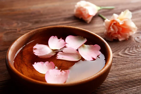 Petali rosa rosa in una ciotola d'acqua su sfondo di legno — Foto Stock