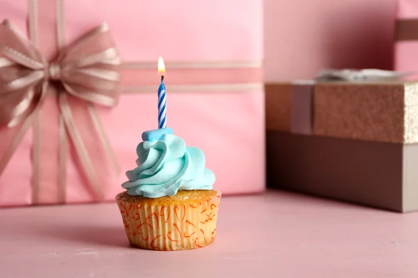 Édes cupcake gyertya rózsaszín jelen dobozok háttér — Stock Fotó