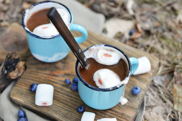 Choklad med marshmallow i muggar på marken — Stockfoto