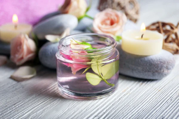 Komposition von Blumen, Kerzen und Steinen auf weißem Holzgrund, im Wellness-Salon — Stockfoto