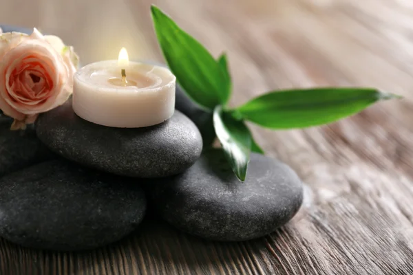 Spa composition of candles, flowers and stones on brown wooden background — Stock Photo, Image