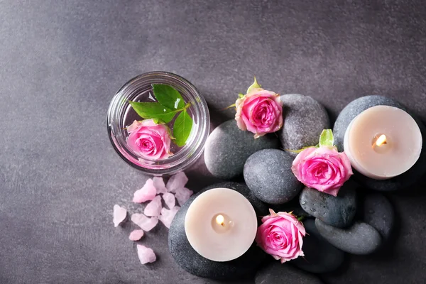 Composición spa de velas, piedras y flores, sobre fondo gris — Foto de Stock