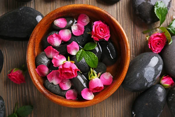 Composición spa de piedras y flores en agua, sobre fondo de madera — Foto de Stock