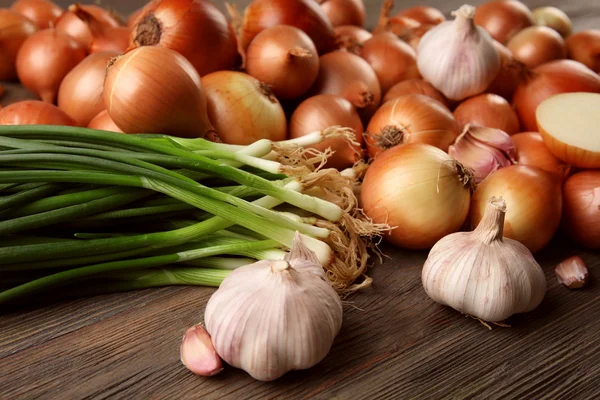 Fresh different onions with garlic on wooden background — Stock Photo, Image