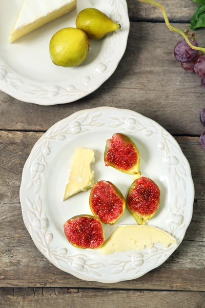 Ripe figs and cheese on plate, on wooden background — Stock Photo, Image