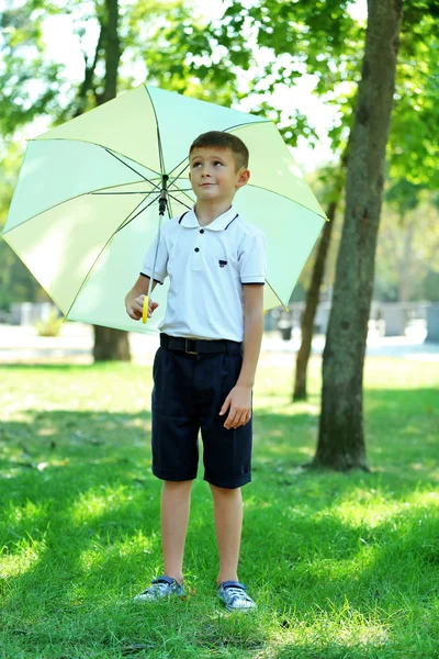 Мальчик под большим кремовым зонтиком — стоковое фото