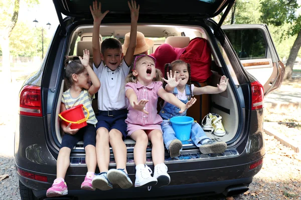 Enfants heureux assis sur le coffre de la voiture — Photo