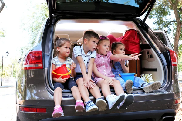 Crianças felizes sentam-se no tronco do carro — Fotografia de Stock