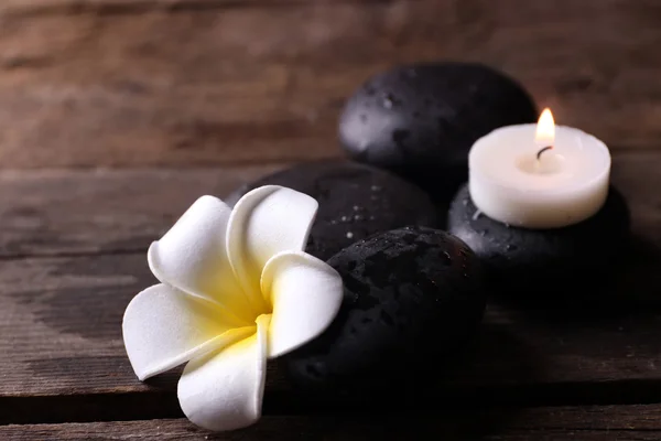 Ontspannen concept - fragipani bloem, keien en kaarsen op houten achtergrond — Stockfoto