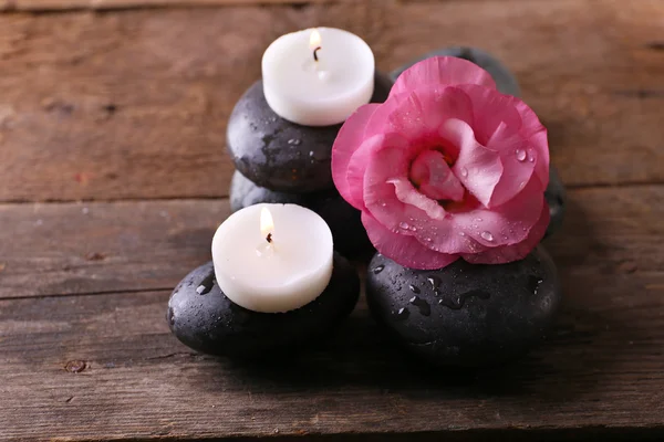 Brennende Kerzen, Kieselsteine und frische Duftblumenkomposition auf Holzgrund — Stockfoto