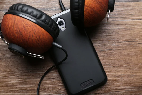 Auriculares y smartphone sobre fondo de madera marrón —  Fotos de Stock