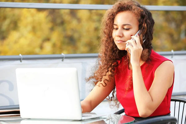Affärskvinna med laptop talar av mobiltelefon — Stockfoto