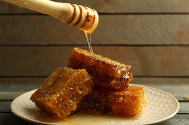 Ahşap arka plan üzerinde peteğin damlayan bal