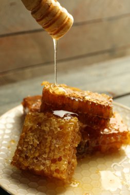 Ahşap arka plan üzerinde peteğin damlayan bal