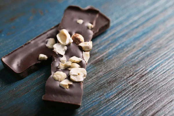 Piezas de chocolate negro con nueces sobre fondo de madera de color —  Fotos de Stock