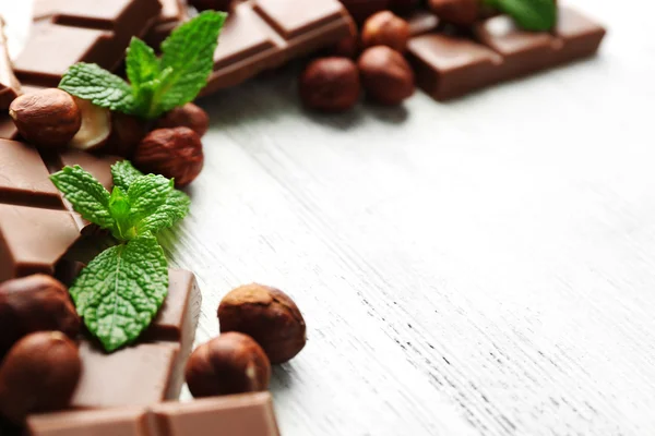 Čokoládové kousky s ořechy na barevné dřevěné pozadí — Stock fotografie