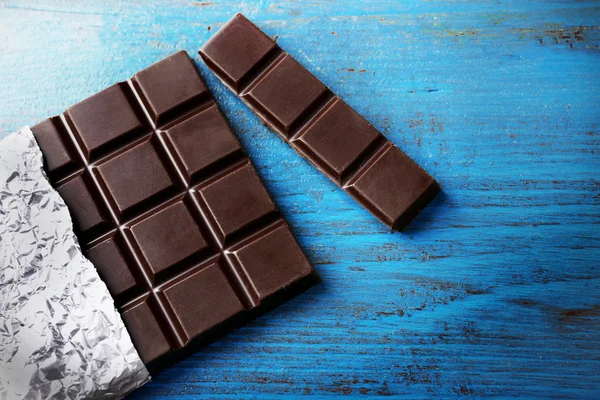 Tmavé čokolády v alobalu na šedém pozadí — Stock fotografie