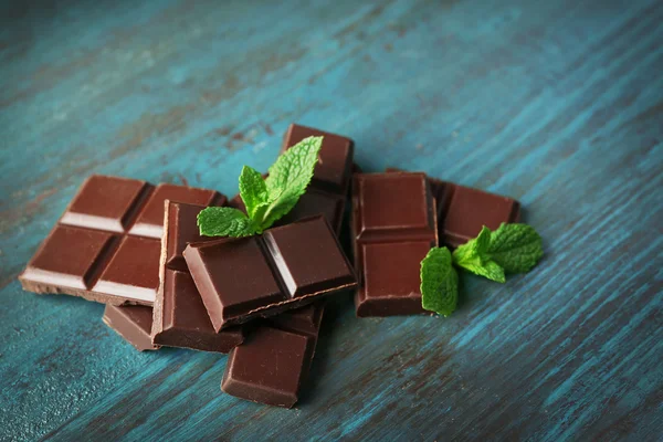 Svart choklad bitar på färg trä bakgrund — Stockfoto