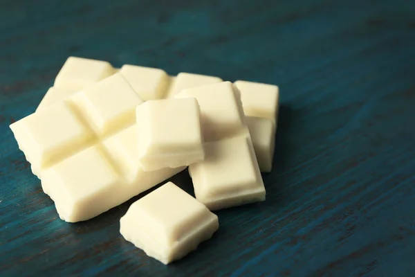 White chocolate pieces on color wooden background — Stock Photo, Image