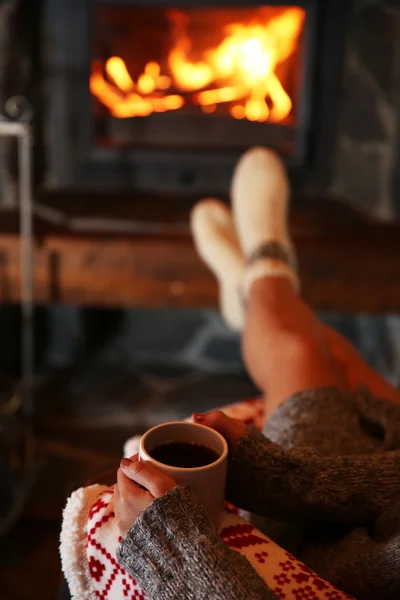 Mujer con taza de bebida caliente cerca de la chimenea — Foto de Stock