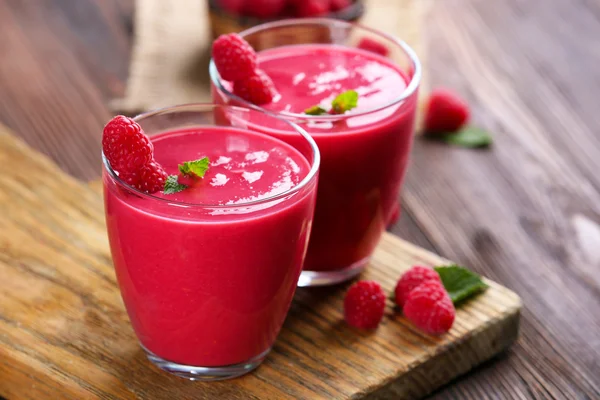 Glasses of raspberry milk shake with berries on wooden table close up — Stock Photo, Image