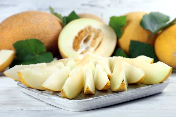 Ripe melons with green leaves on wooden table close up — Stock Photo, Image