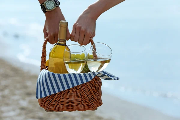 年轻的夫妇在沙滩上举行野餐篮子与瓶酒 — 图库照片