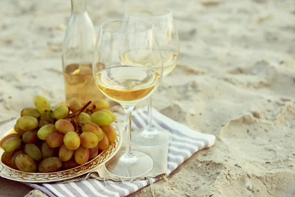 Composizione romantica di vino bianco e uva sulla spiaggia sabbiosa — Foto Stock