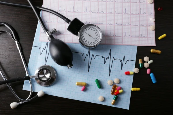 Měřič krevního tlaku a stetoskop, na tmavé dřevěné pozadí — Stock fotografie