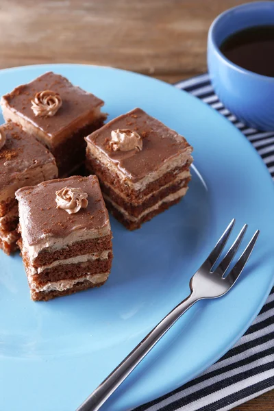 Słodkie ciasto czekoladowe na niebieski płyta na drewnianym stole — Zdjęcie stockowe