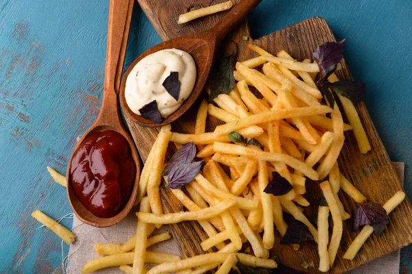 Batatas fritas francesas com molho na tábua de corte — Fotografia de Stock