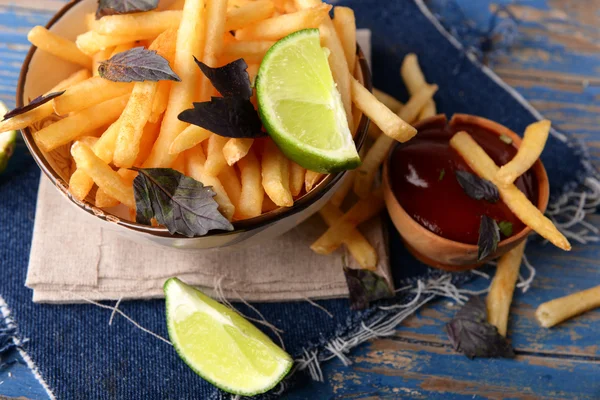 Pommes de terre frites dans un bol avec basilic et sauce sur un vieux fond en bois — Photo