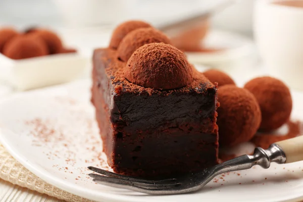 Rebanada de pastel de chocolate con una trufa en el primer plano del plato — Foto de Stock