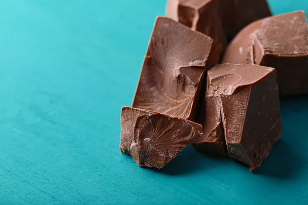 Pedaços de chocolate de leite na cor de fundo de madeira — Fotografia de Stock