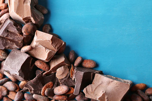 Gelap dan susu coklat potongan dan biji kakao pada warna latar belakang kayu — Stok Foto