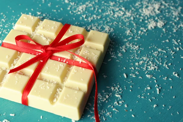 White chocolate bar with coconut shavings on color wooden background — Stock Photo, Image