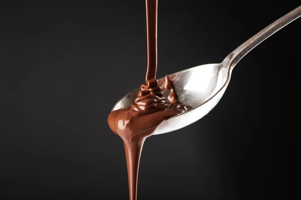 Chocolate poured on a spoon on dark background — Stock Photo, Image