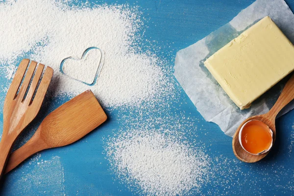 Heart of flour and  wooden kitchen utensils on blue background — Stock Photo, Image