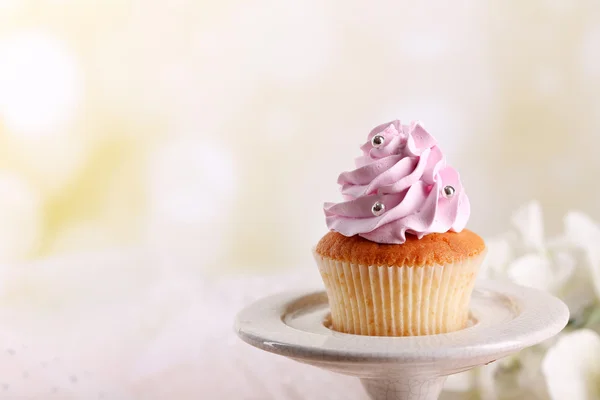 Smakelijke cupcake op stand, op lichte achtergrond — Stockfoto