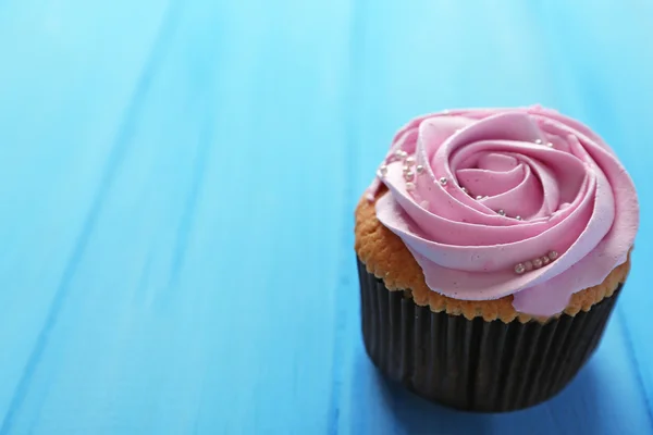 Leckere Cupcake auf farbigem Holzhintergrund — Stockfoto