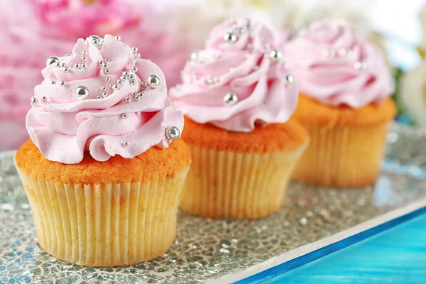 Leckere Cupcakes auf Teller, auf farbigem Holzhintergrund — Stockfoto