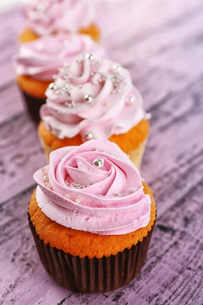 Smakelijke cupcakes op een houten achtergrond kleur — Stockfoto