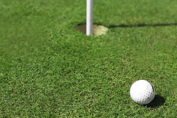 Bola de golfe no lábio do copo no campo de golfe verde — Fotografia de Stock