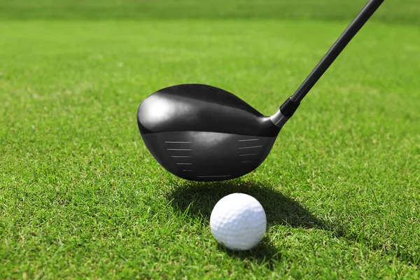 Golf club och bollen på ett grönt gräs — Stockfoto