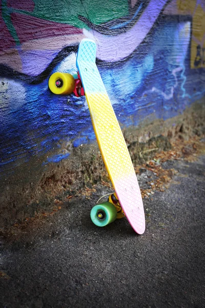 Skating board near the painted wall background — Stock Photo, Image