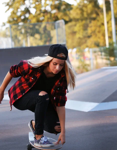 Mujer joven con tabla de patinar en la carretera —  Fotos de Stock