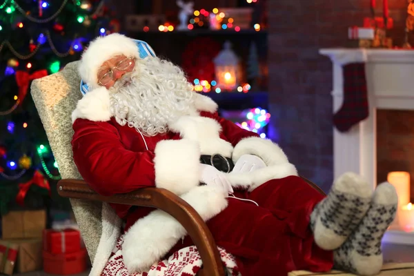 圣诞老人坐着耳机坐在舒适的摇椅上在家里 — 图库照片