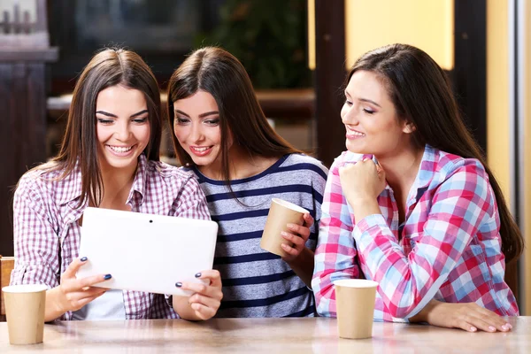 Tres amigos sonrientes con café mirando la tableta —  Fotos de Stock