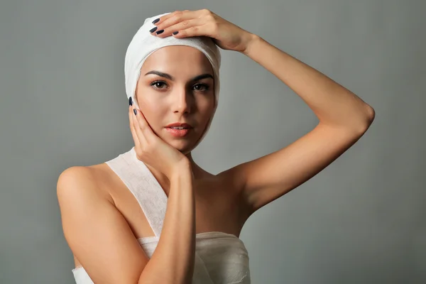 Jeune femme émotionnelle avec un bandage de gaze sur la tête et la poitrine, sur fond gris — Photo